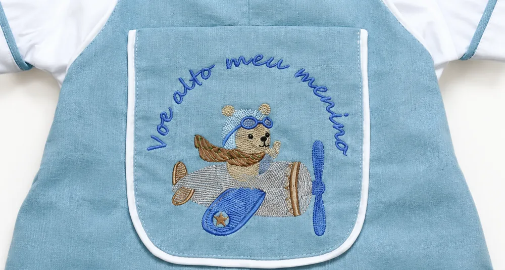 Frase bordada em arco sobre o ursinho aviador